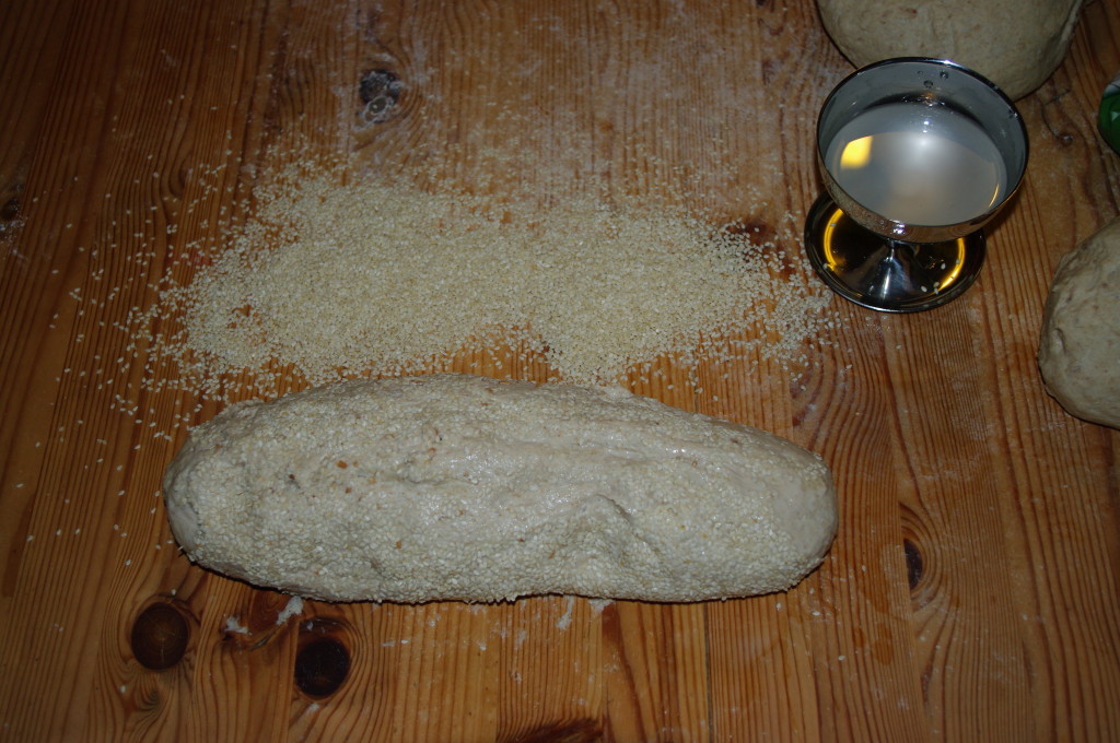 De utbakte brødene blir litt fuktet og så rullet i sesamfrø.